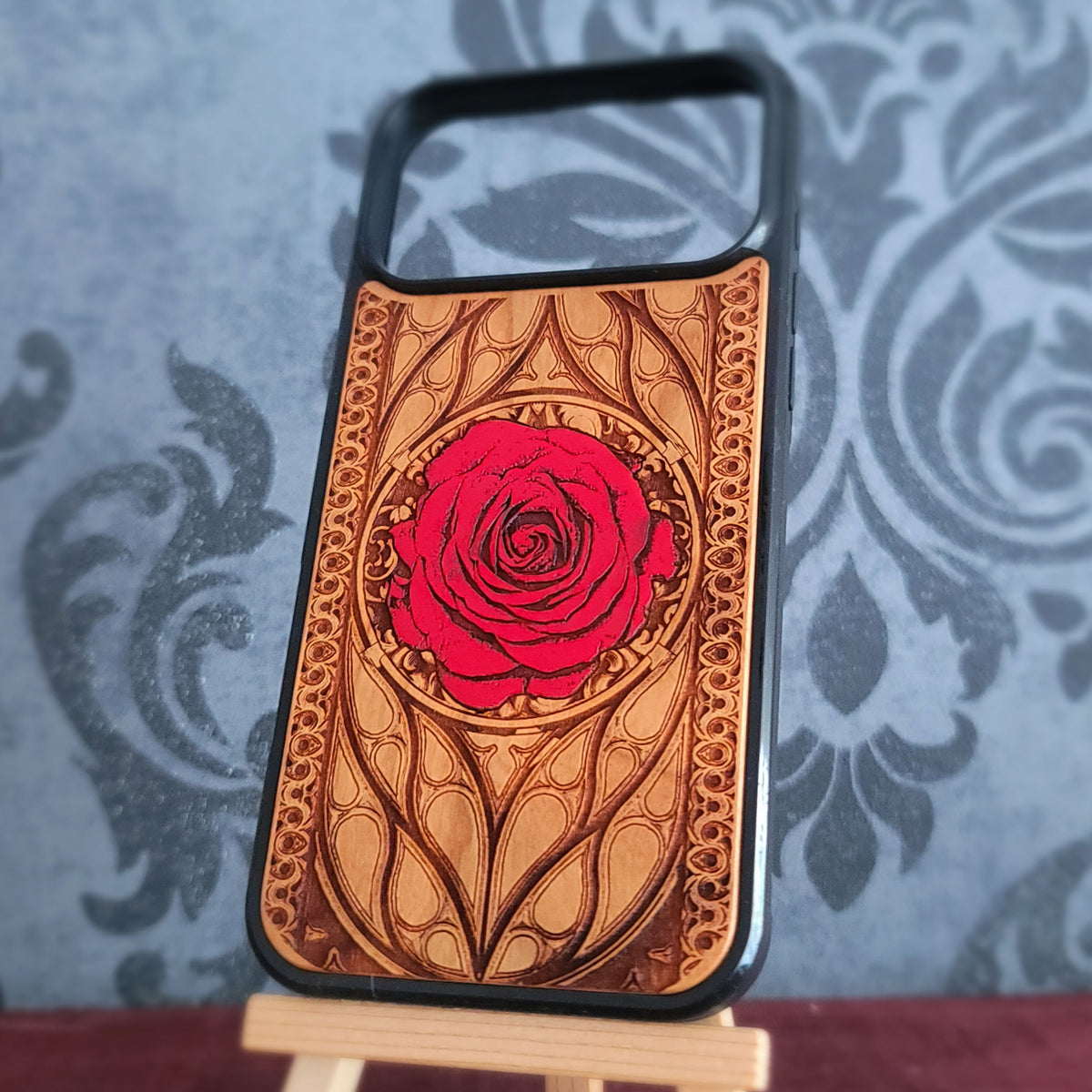 A wooden phone case with a carved red rose design, 
