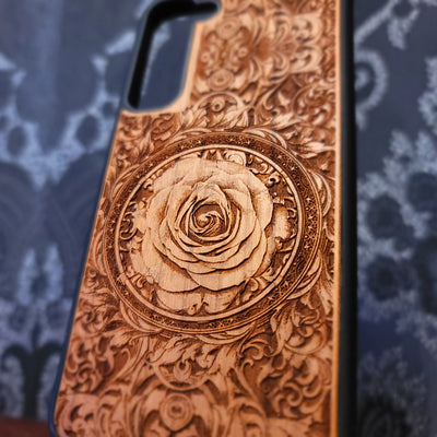 Deep laser engraved wooden phone case featuring an intricate floral design with a large detailed rose on natural wood for iPhone and Samsung Galaxy models.
