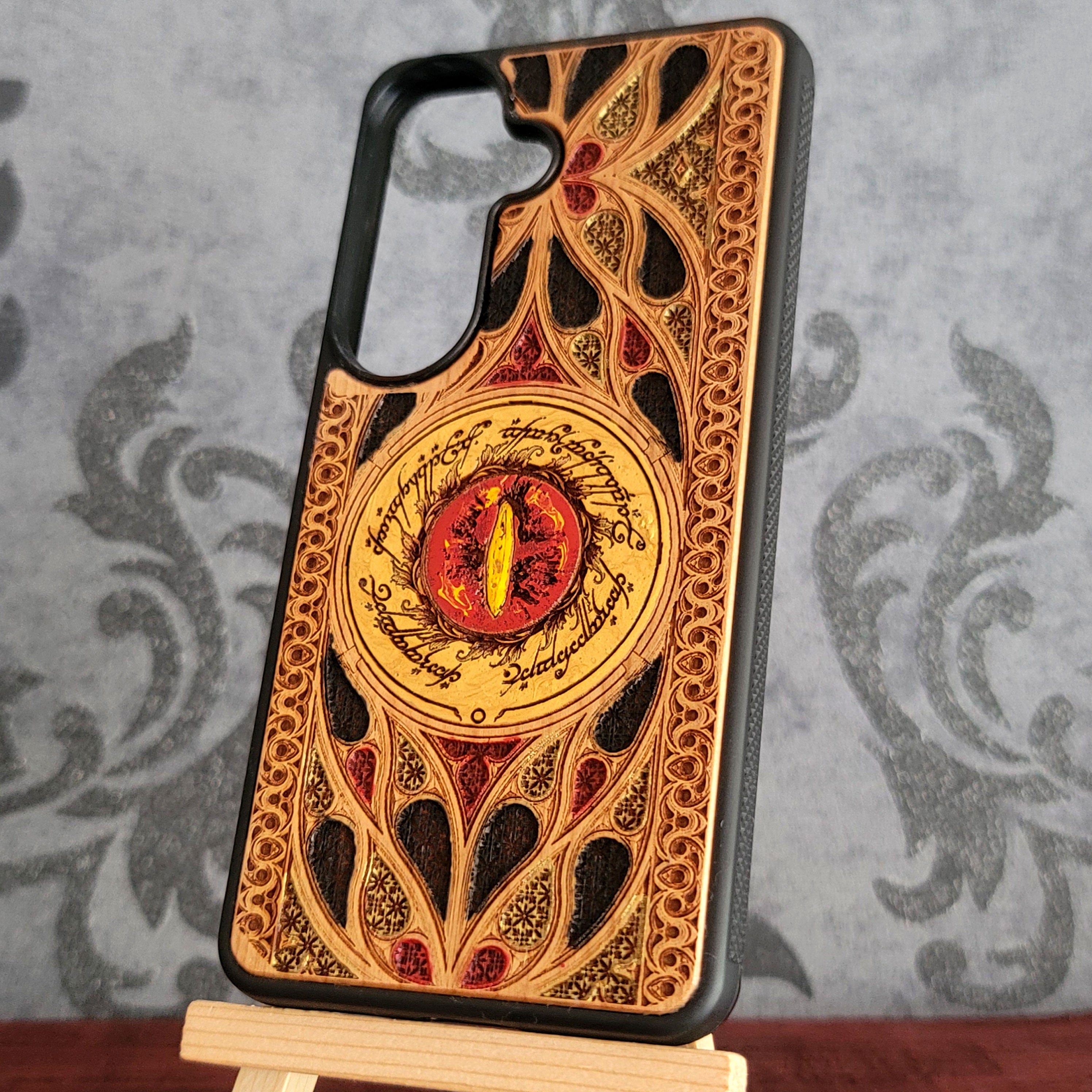 Hand-painted wood phone case featuring the Eye of Sauron surrounded by intricate Elvish script and vibrant colored patterns. 
