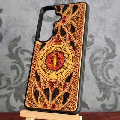 Hand-painted wood phone case featuring the Eye of Sauron surrounded by intricate Elvish script and vibrant colored patterns. 