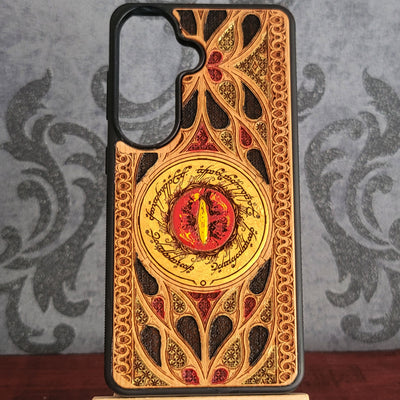 Hand-painted wood phone case featuring the Eye of Sauron surrounded by intricate Elvish script and vibrant colored patterns. 