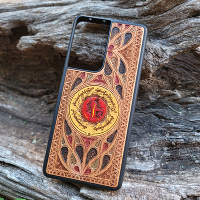 "Hand-painted wood phone case featuring the Eye of Sauron surrounded by intricate Elvish script and vibrant colored patterns. This laser-engraved and detailed design offers a unique blend of artistry and durability. Compatible with iPhone , 15, 14, 13, 12, 11, Pro Max, Mini, and Samsung Galaxy S, S24, S23, S22, S21, S20 Ultra, Plus, Note 20. Perfect for Lord of the Rings fans seeking a bold and protective accessory