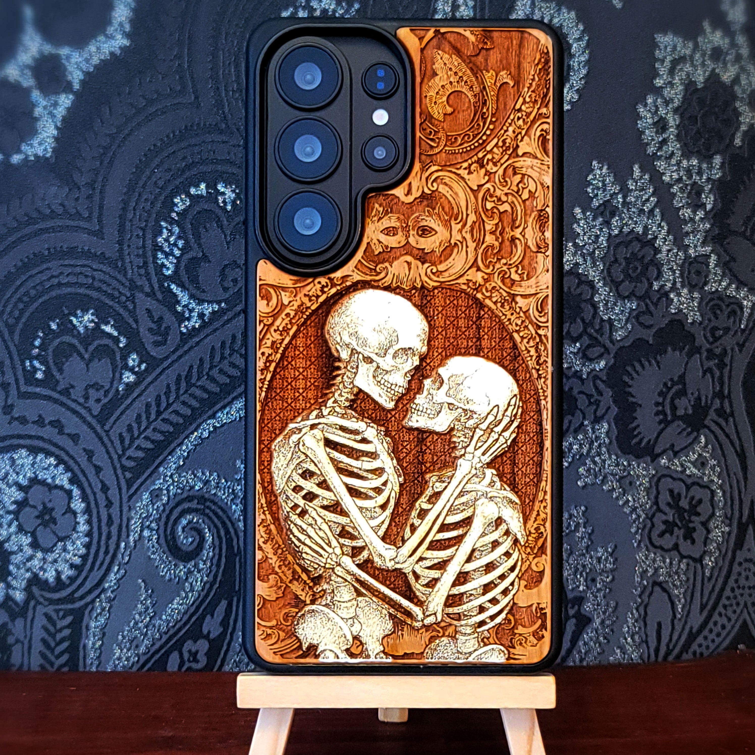 Gothic skeleton couple kissing engraved on wood phone case, romantic dark art design for iPhone 16 & Galaxy S25.
