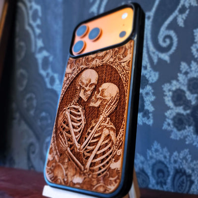 Gothic skeleton couple kissing engraved on wood phone case, romantic dark art design for iPhone 16 & Galaxy S25.