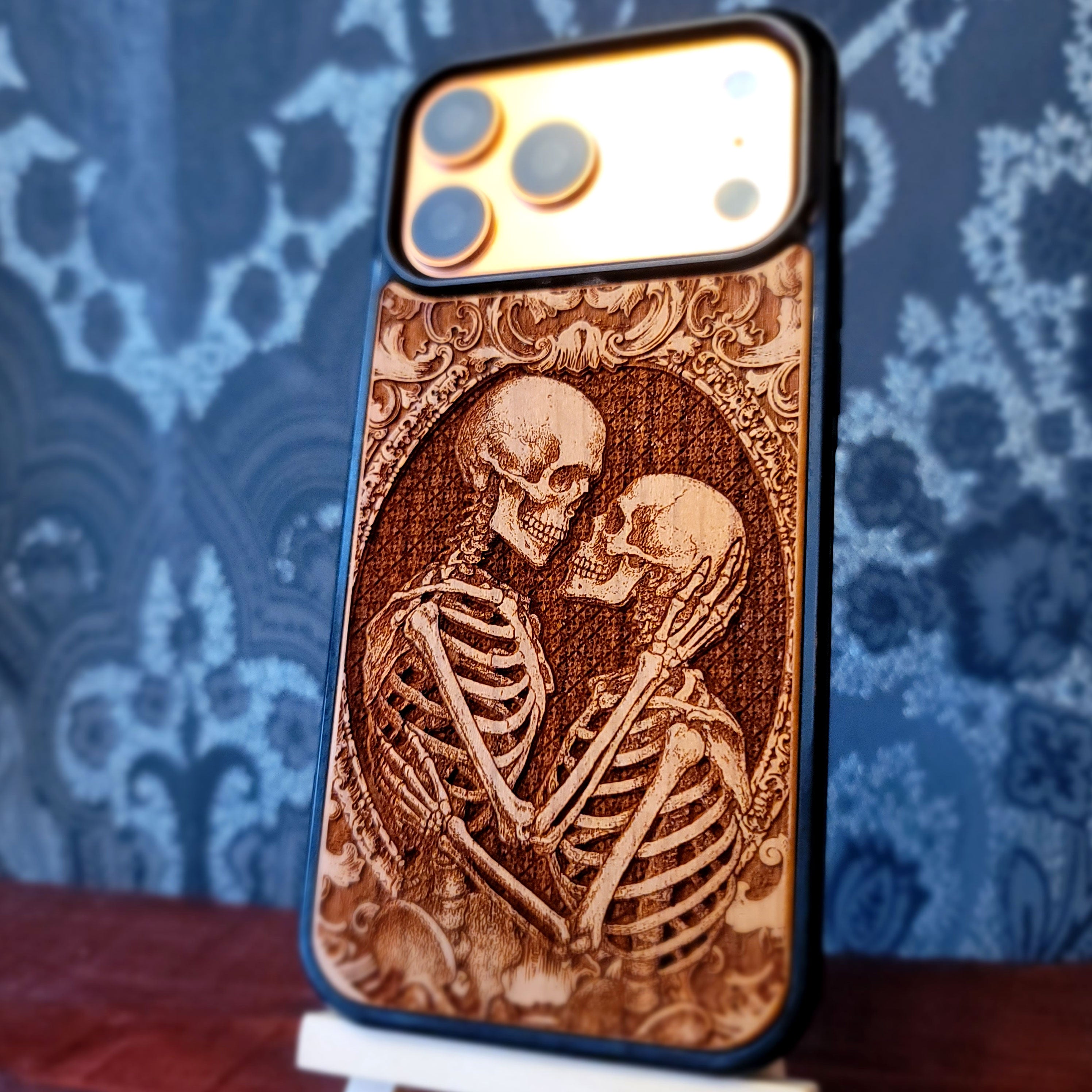 Gothic skeleton couple kissing engraved on wood phone case, romantic dark art design for iPhone 16 & Galaxy S25.