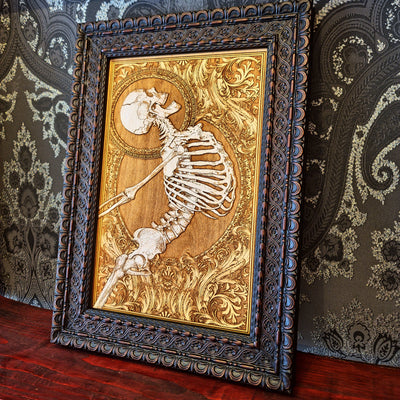 Decorative framed artwork with a skeleton design on a patterned wall background