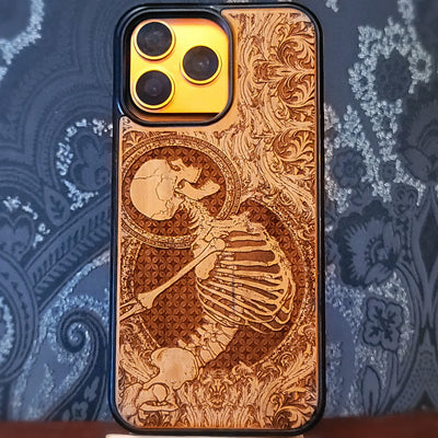 Deep laser engraved wooden phone case featuring a happy skeleton design on natural wood for iPhone and Samsung Galaxy models.