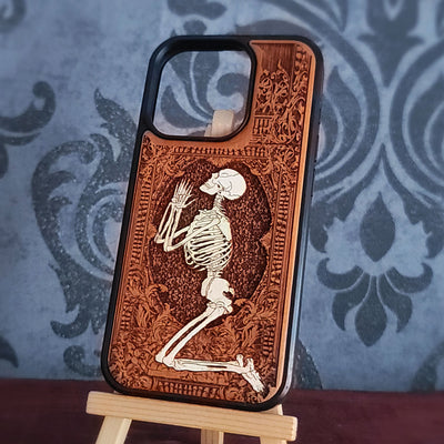 Hand-painted wooden phone case featuring a laser-engraved and hand painted praying skeleton design on cherrywood. 