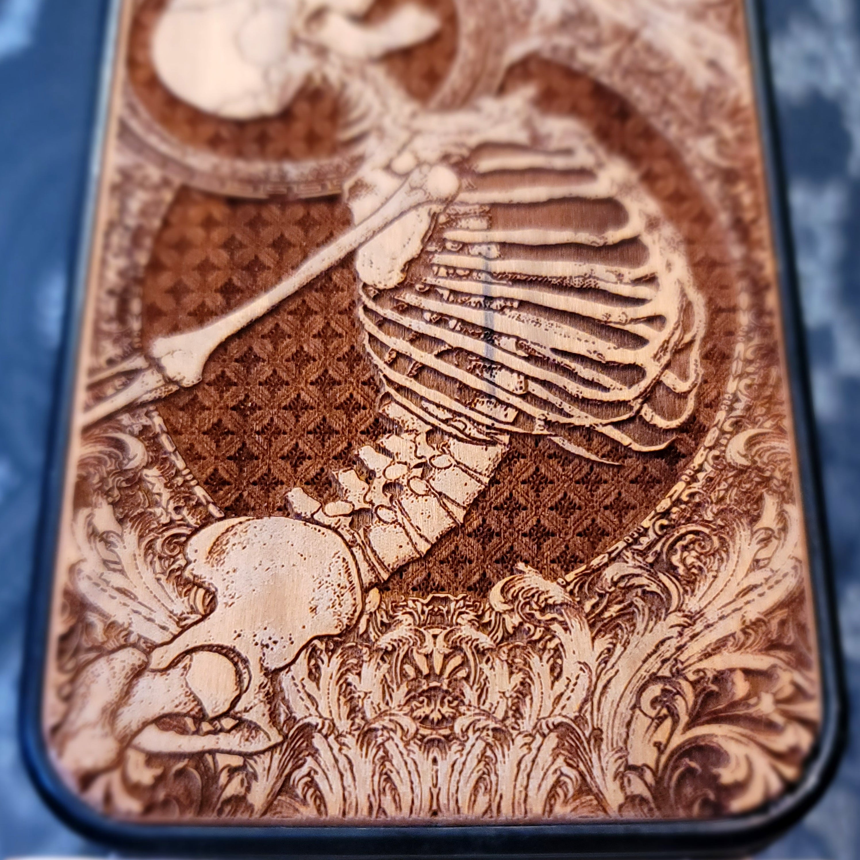 Deep laser engraved wooden phone case featuring a happy skeleton design on natural wood for iPhone and Samsung Galaxy models.