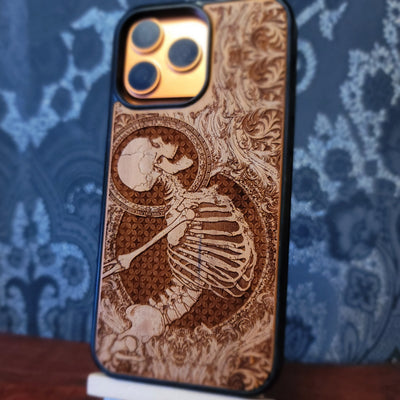 Deep laser engraved wooden phone case featuring a happy skeleton design on natural wood for iPhone and Samsung Galaxy models.