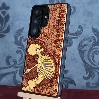 Cherry wood phone case with laser-engraved Gothic skeleton design for iPhone & Samsung Galaxy.