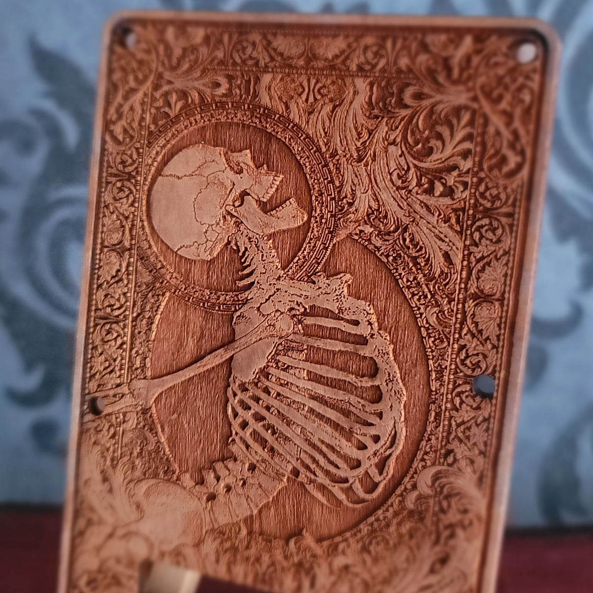 Close up of anatomical skeleton artwork engraved into natural cherry wood tremolo cover
