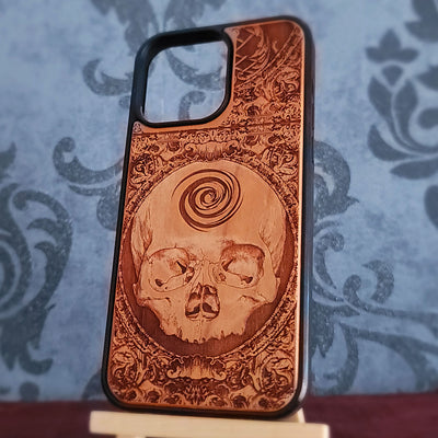 A wooden phone case with a laser-engraved skull and spiral design, 
