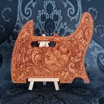 A wooden guitar pickguard with an intricate laser-etched design featuring a skeletal figure and floral patterns.