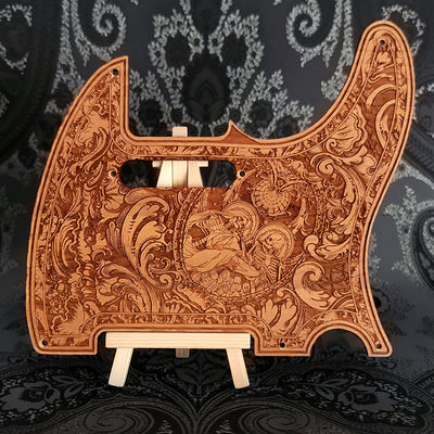A wooden guitar pickguard with an intricate laser-etched design featuring a skeletal figure and floral patterns.