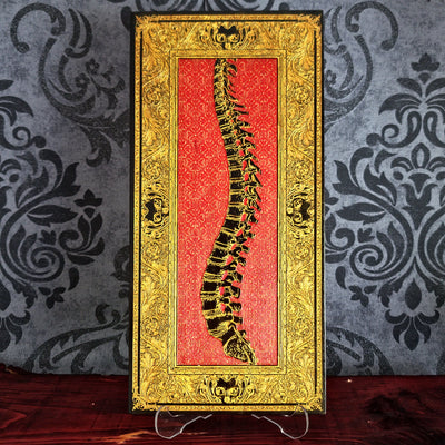 Decorative book with a spine illustration on a red background, framed in gold against a patterned wall.