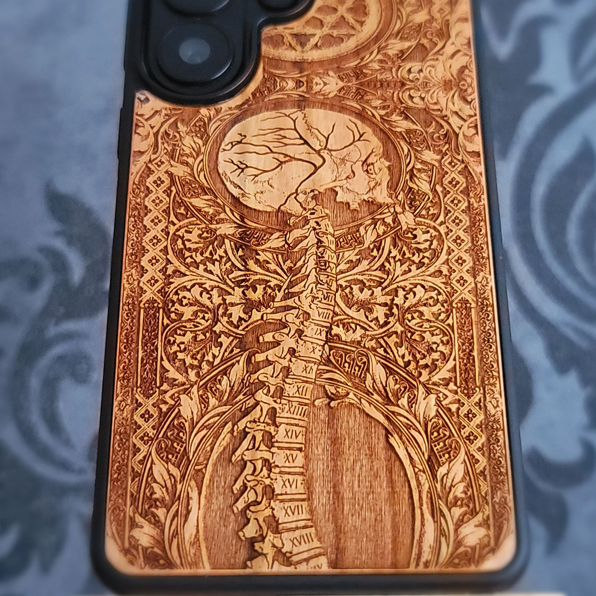 Natural cherrywood anatomical phone case showing detailed laser engraving and real wood grain