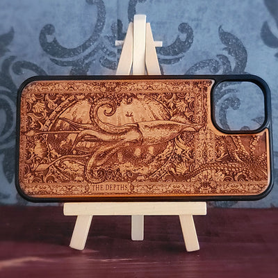 A rectangular wooden phone case with a carved octopus design and the text 'THE DEPTHS' at the bottom