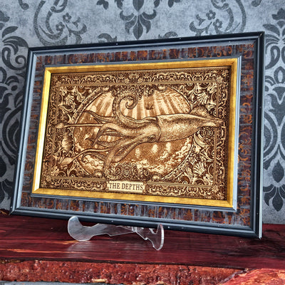 A framed decorative artwork featuring a raised octopus or squid-like marine creature with the words 'THE DEPTHS' at the bottom, displayed on a stand against a patterned wallpaper background.