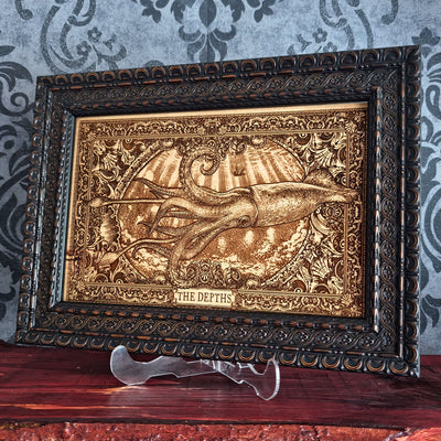An ornate framed decorative art piece featuring a raised octopus emerging from water, with the words 'THE DEPTHS' at the bottom. The piece has a dark carved frame and is displayed on a clear stand against a patterned wallpaper background.