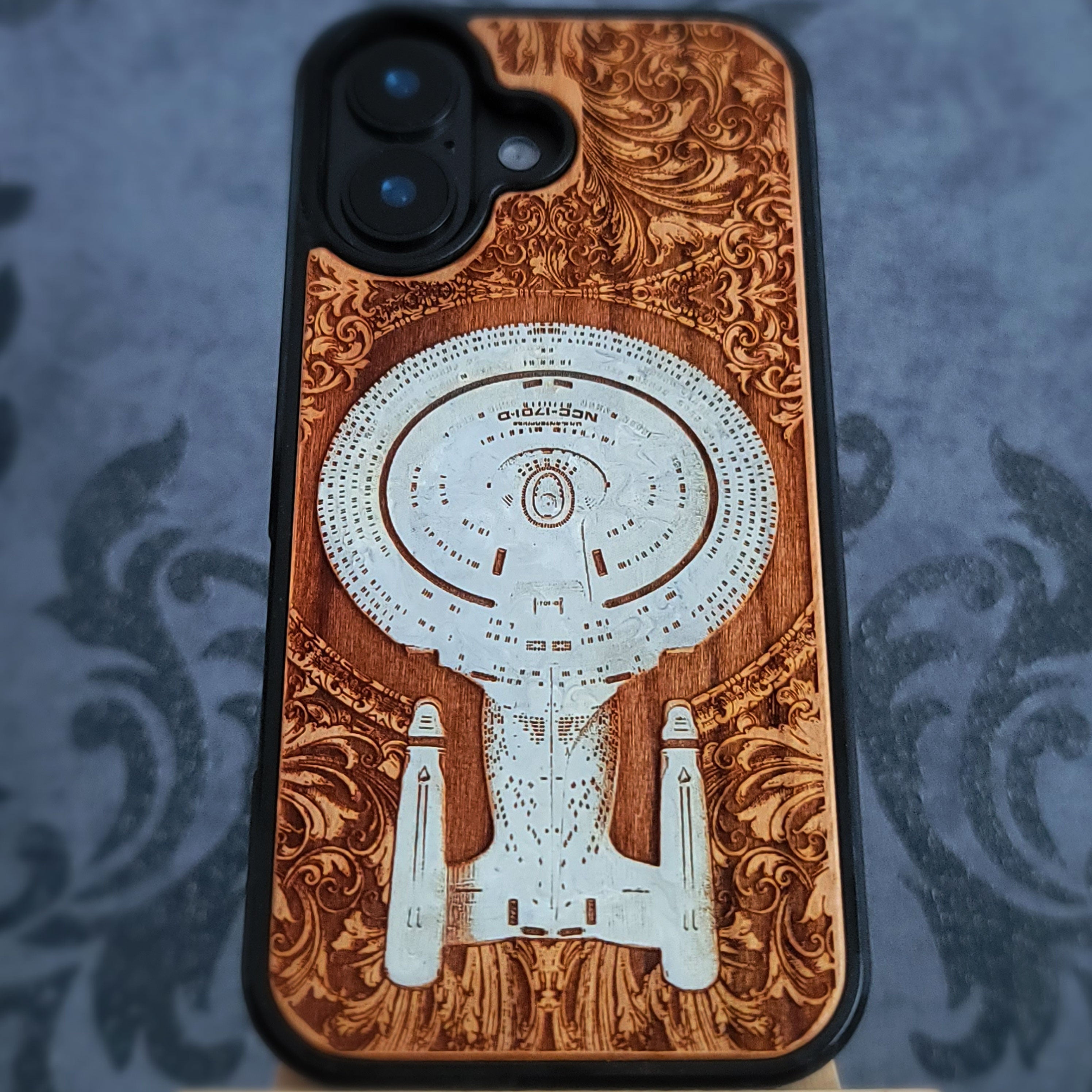 Enterprise NCC-1701-D hand-painted cherrywood phone case, angled rear view showing the painted saucer section