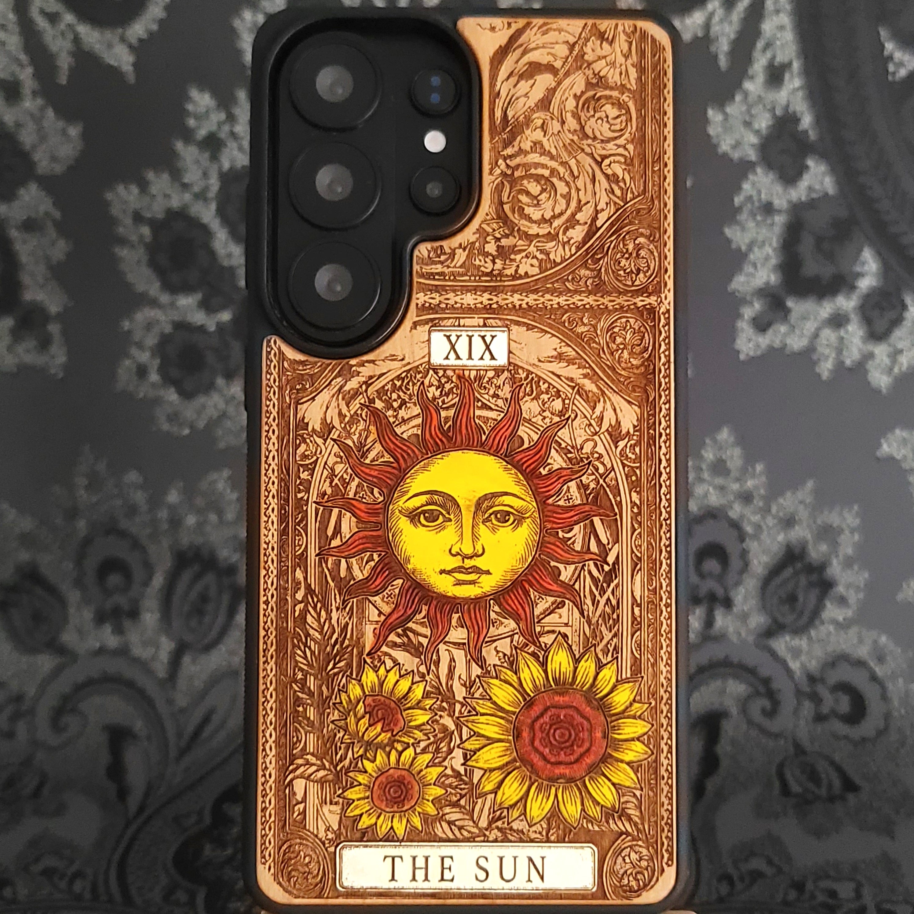 Deep laser engraved wooden phone case featuring The Sun tarot card with celestial mystical details on natural wood for iPhone and Samsung Galaxy models.
