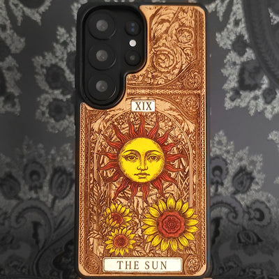 Deep laser engraved wooden phone case featuring The Sun tarot card with celestial mystical details on natural wood for iPhone and Samsung Galaxy models.