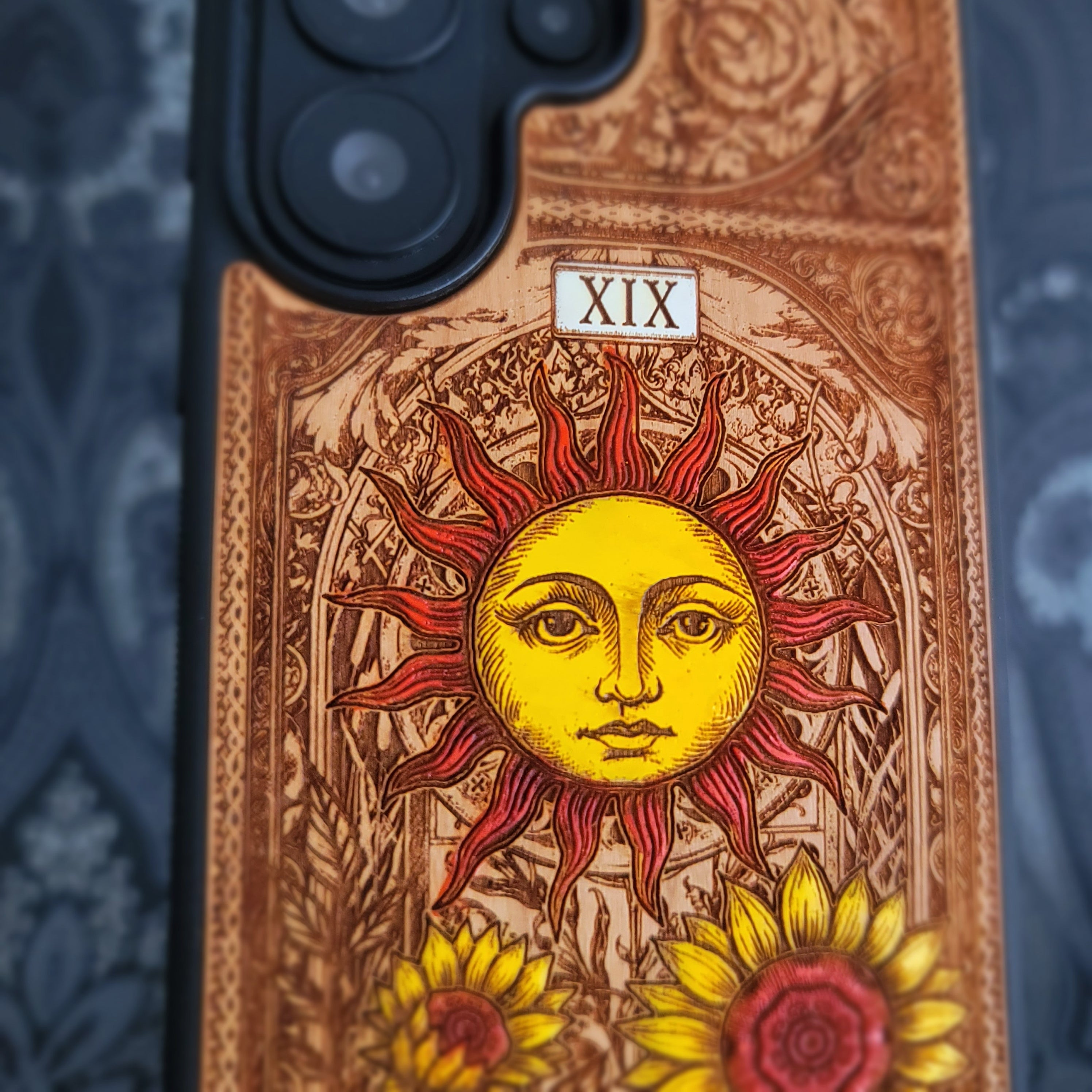 Deep laser engraved wooden phone case featuring The Sun tarot card with celestial mystical details on natural wood for iPhone and Samsung Galaxy models.