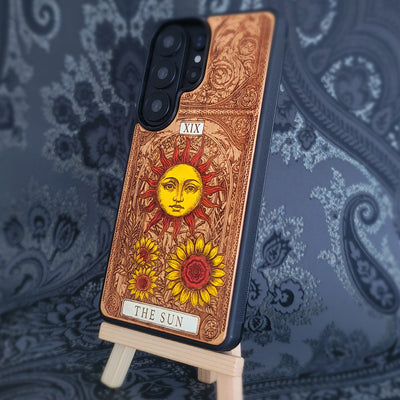 Deep laser engraved wooden phone case featuring The Sun tarot card with celestial mystical details on natural wood for iPhone and Samsung Galaxy models.