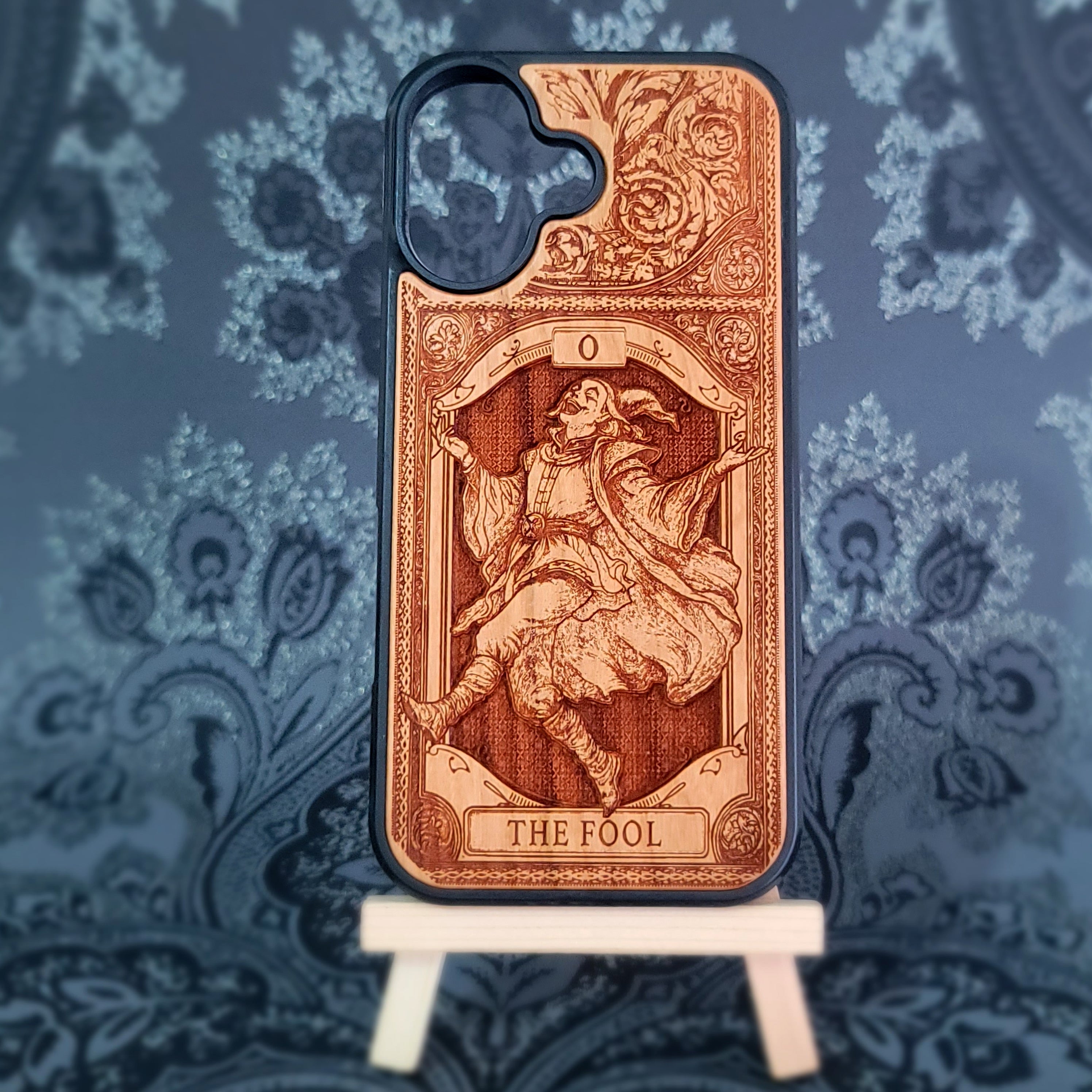 Deep laser engraved wooden phone case featuring The Fool tarot card with mystical celestial details on natural wood for iPhone and Samsung Galaxy models.