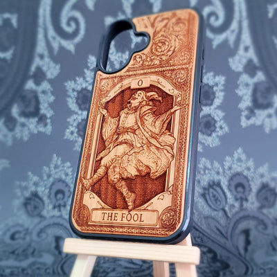 Deep laser engraved wooden phone case featuring The Fool tarot card with mystical celestial details on natural wood for iPhone and Samsung Galaxy models.