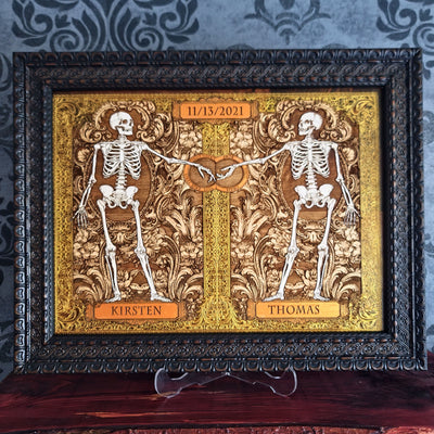 Skeleton couple wood art with ornate golden leaf frame