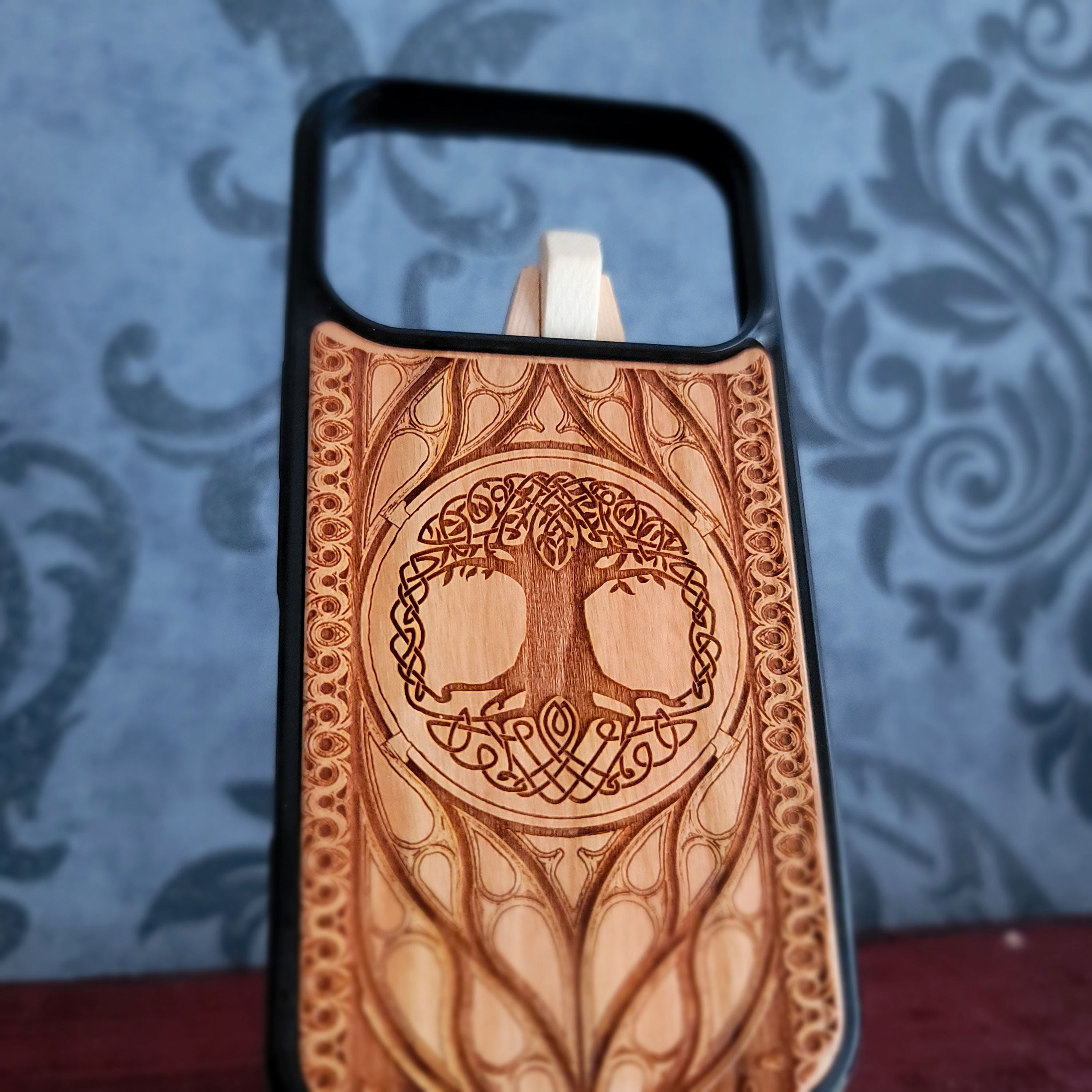 Wood phone case featuring a laser-engraved Tree of Life design surrounded by intricate Celtic-inspired patterns.