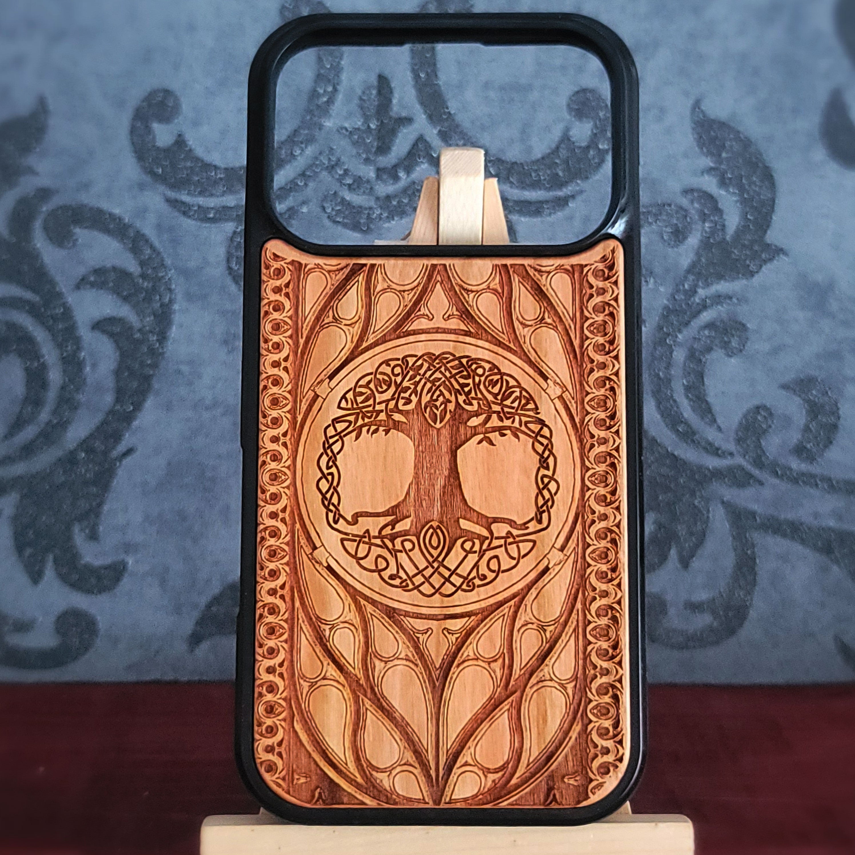 Wood phone case featuring a laser-engraved Tree of Life design surrounded by intricate Celtic-inspired patterns.