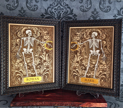 Two framed gothic-style skeleton art prints with ornate gold and black frames, displayed side-by-side 