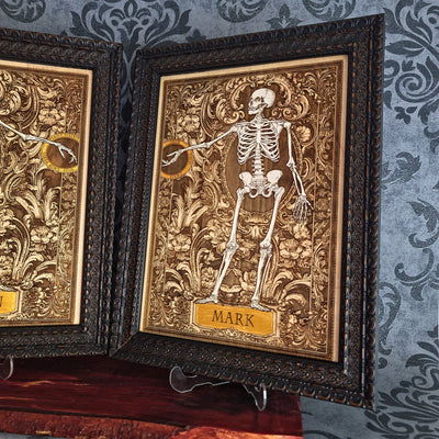 Two framed gothic-style art prints featuring skeleton figures over ornate gold and brown baroque-style backgrounds, 