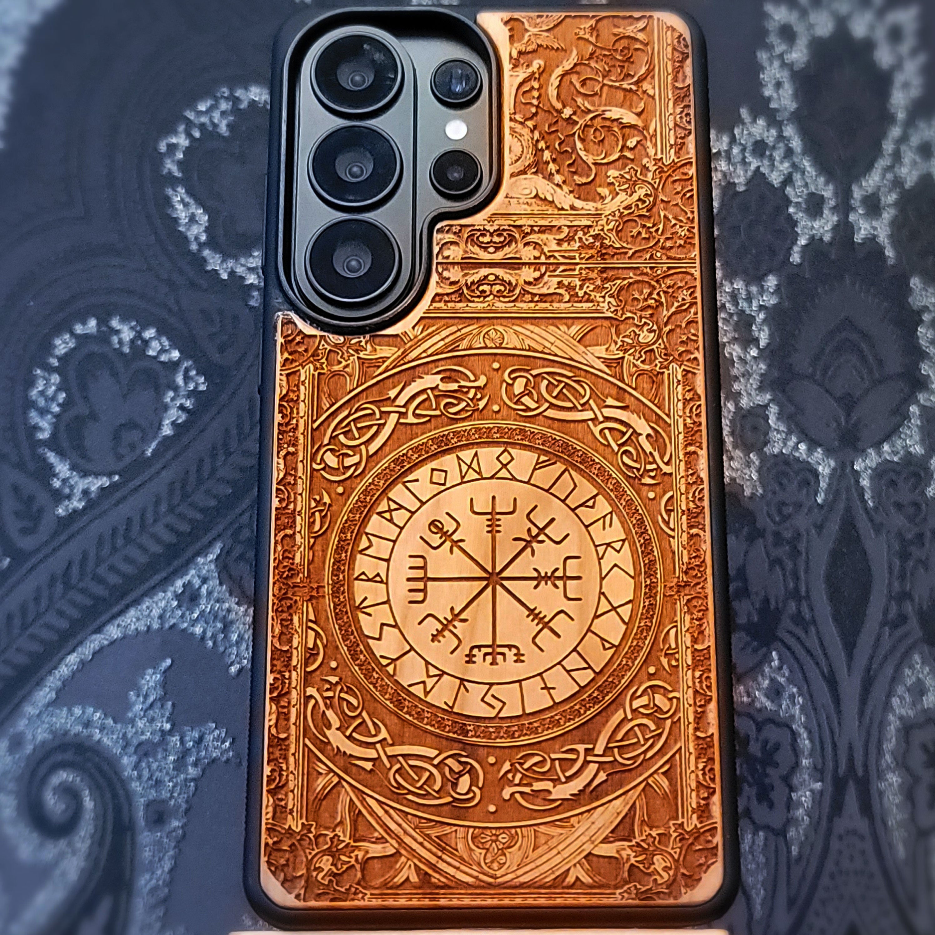 Deep laser engraved wooden phone case featuring the Vegvisir Viking compass with Nordic runic symbols for iPhone and Samsung Galaxy models.