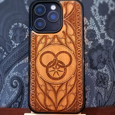 Deep laser engraved wooden phone case featuring a Wheel of Time inspired fantasy symbol on natural wood for iPhone and Samsung Galaxy models.
