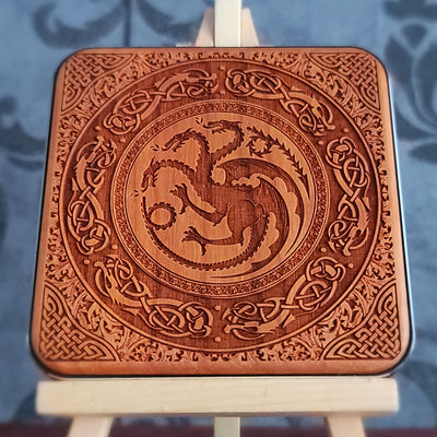 A wooden wireless charger with a laser-etched design of a three-headed dragon surrounded by intricate Celtic knotwork.