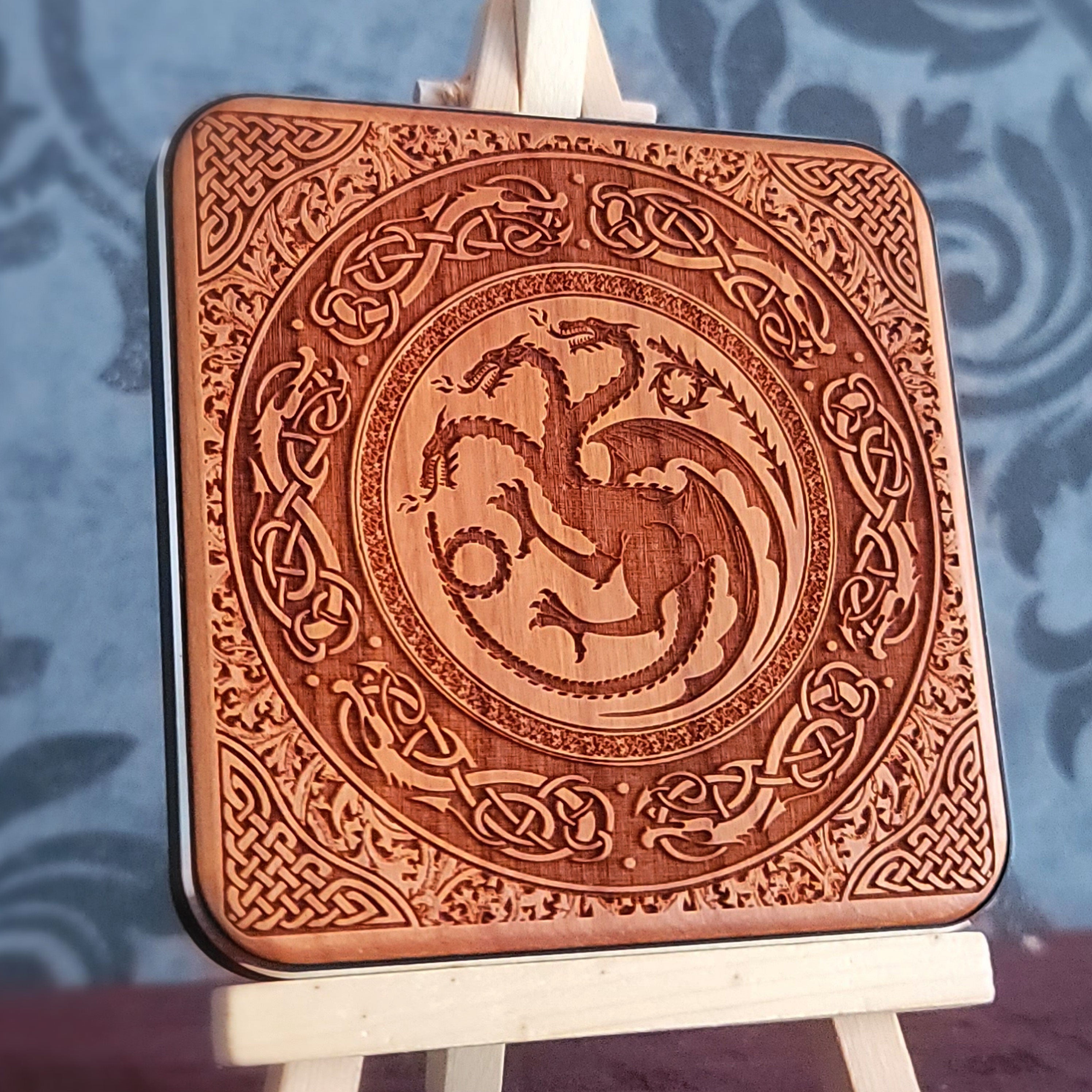 A wooden wireless charger with a laser-etched design of a three-headed dragon surrounded by intricate Celtic knotwork.