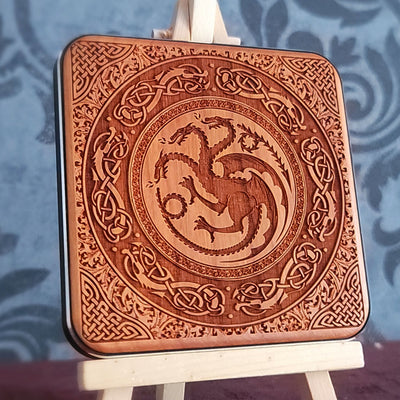 A wooden wireless charger with a laser-etched design of a three-headed dragon surrounded by intricate Celtic knotwork.