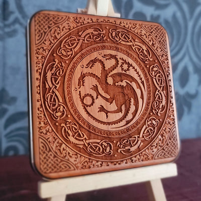 A wooden wireless charger with a laser-etched design of a three-headed dragon surrounded by intricate Celtic knotwork.