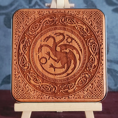 A wooden wireless charger with a laser-etched design of a three-headed dragon surrounded by intricate Celtic knotwork.