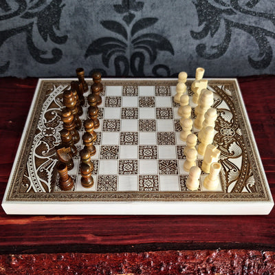 An ornate rectangular chessboard set with carved ivory and dark brown pieces,
