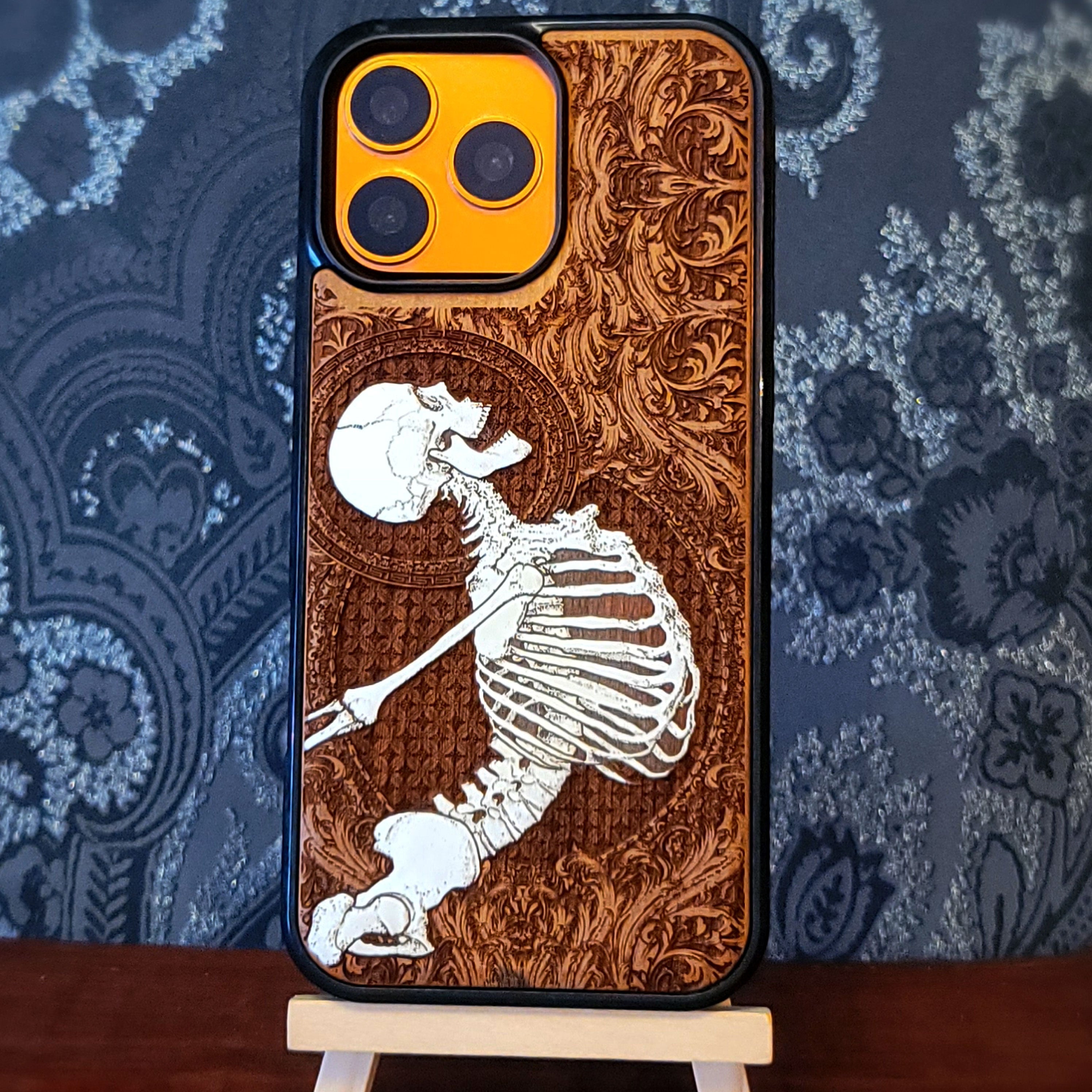 Deep laser engraved wooden phone case featuring a joyful human skeleton design on natural wood for iPhone and Samsung Galaxy.