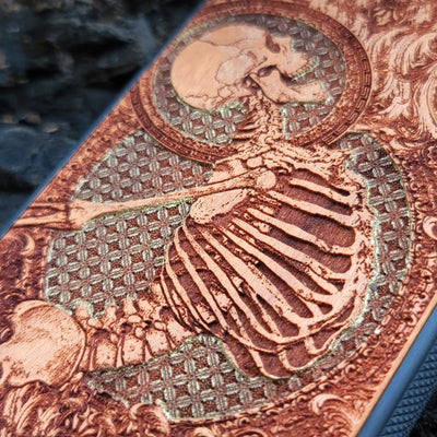 Close-up of Gothic human skeleton engraving on handcrafted cherry wood phone case for iPhone & Galaxy models