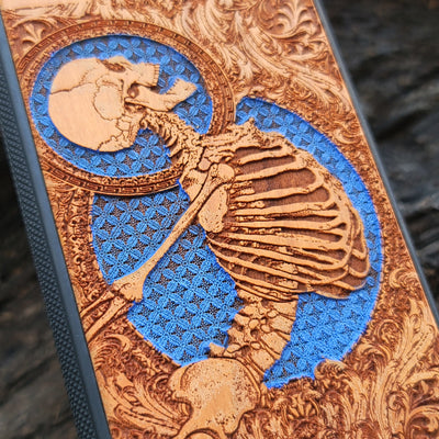 Hand-finished cherry wood phone case with intricate laser-engraved Gothic skeleton art for iPhone & Samsung Galaxy.