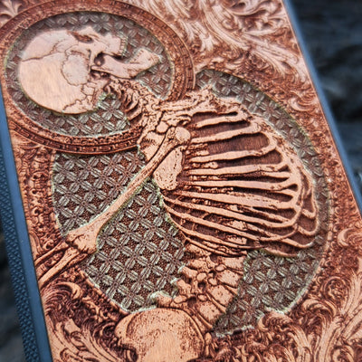 Hand-painted cherry wood phone case with intricate laser engraving of human skeleton and Gothic artwork.