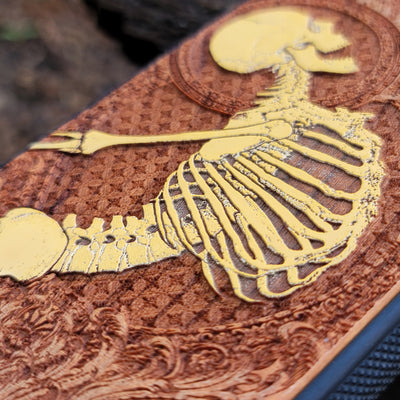 Close-up of intricate Gothic skeleton engraving on hand-finished cherry wood phone case