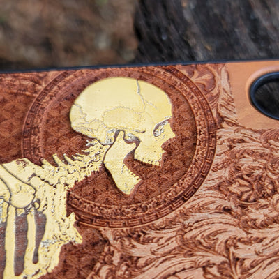 Close-up of intricate Gothic skeleton engraving on hand-finished cherry wood phone case